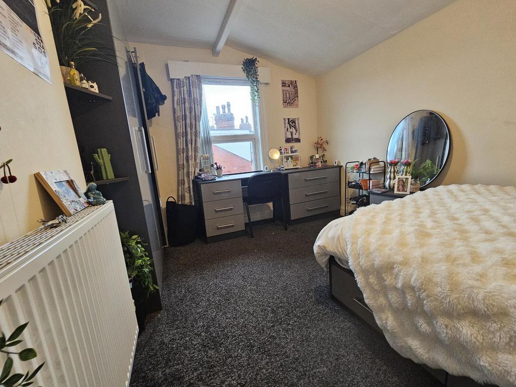 A cozy bedroom featuring a bed, a desk, and a m...