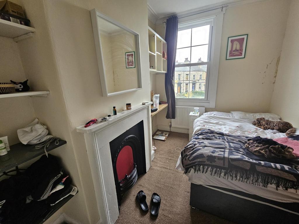 A cozy student bedroom with a comfortable bed, ...