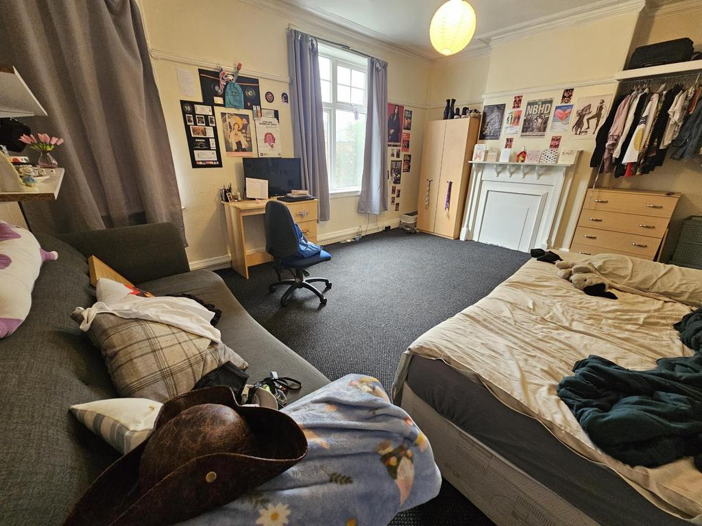 A cozy bedroom featuring a double bed, a desk w...