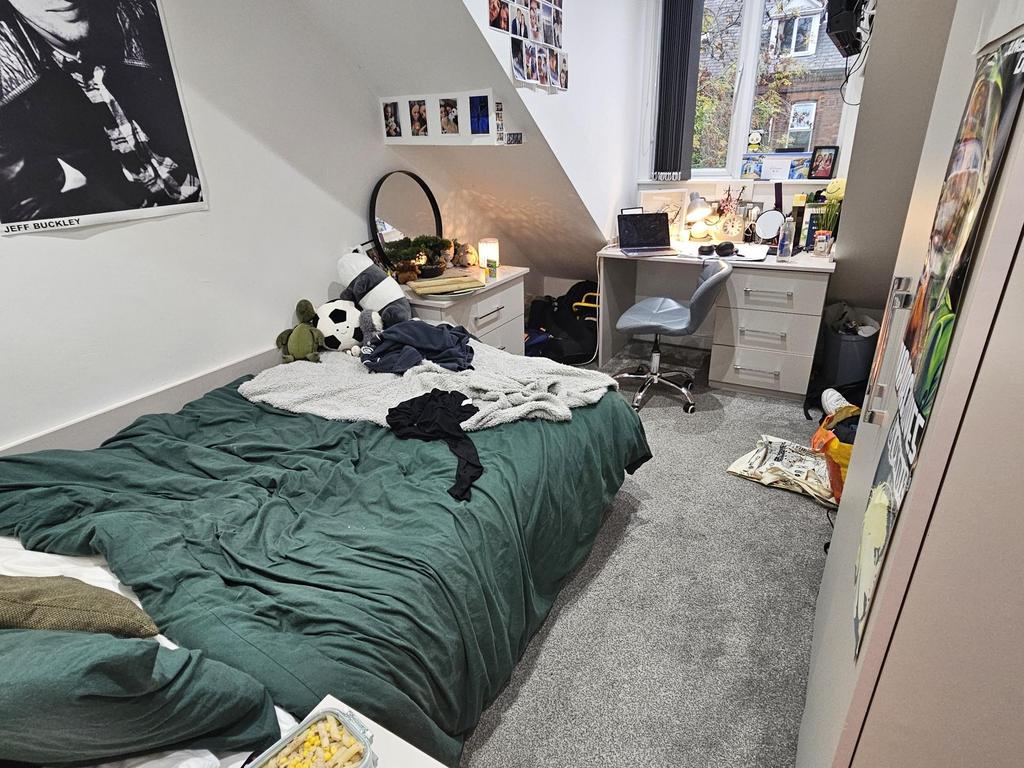 A cozy single bedroom with a neatly made bed, a...