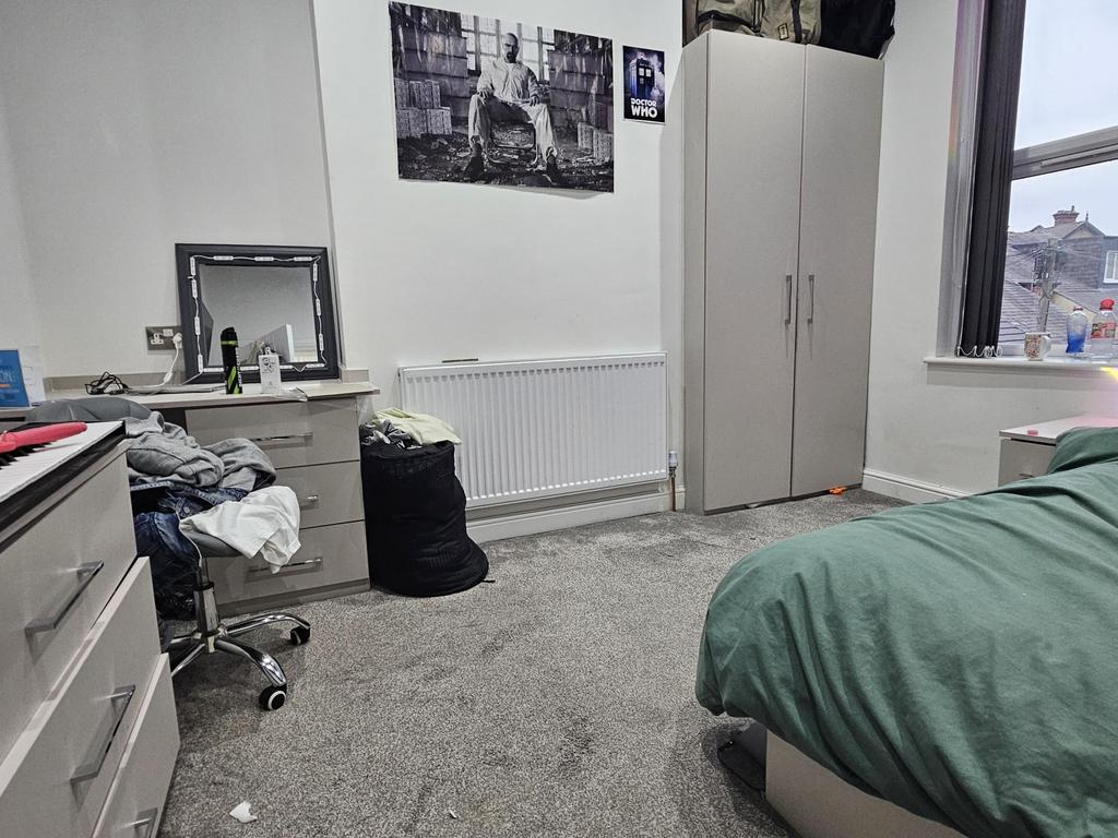 A cozy bedroom with a bed covered in green bedd...