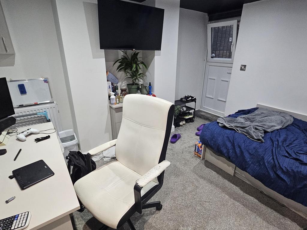 A cozy bedroom featuring a single bed with some...