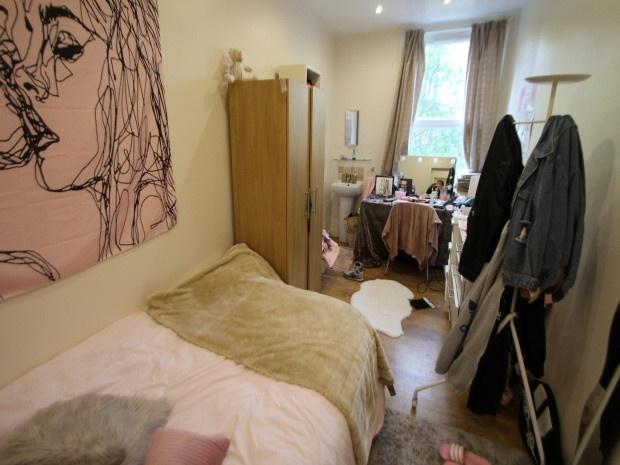 A cozy bedroom featuring a single bed, a wooden...