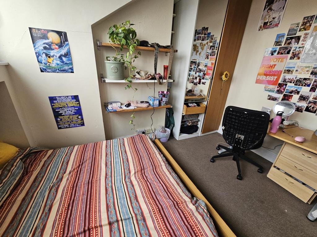 A cozy student bedroom featuring a bed, a desk ...