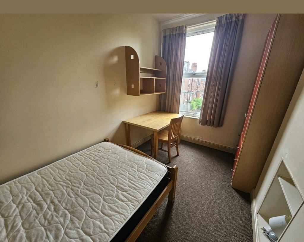 A cozy single bedroom featuring a neat bed and ...