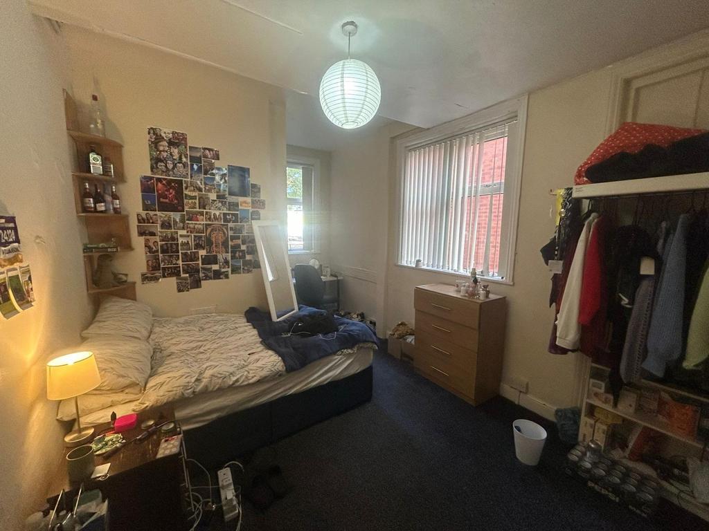 A cozy bedroom with a bed, a desk, and some per...