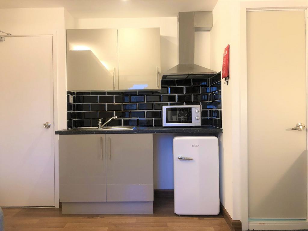 A modern compact kitchen featuring glossy cabin...