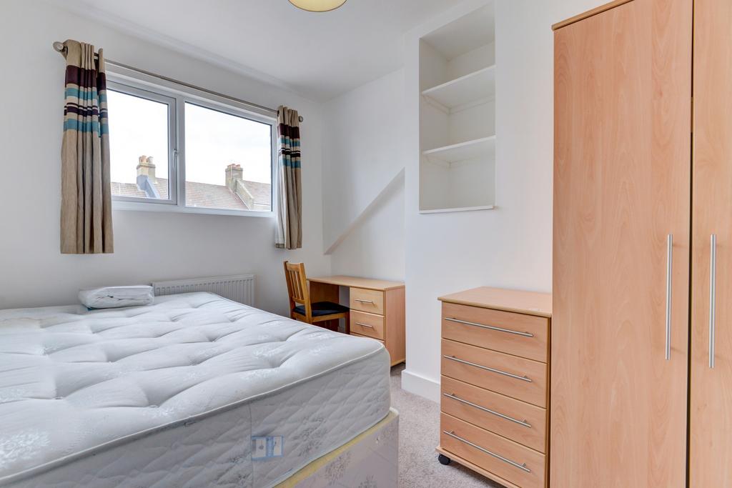 Bright, neatly furnished bedroom with a comfort...