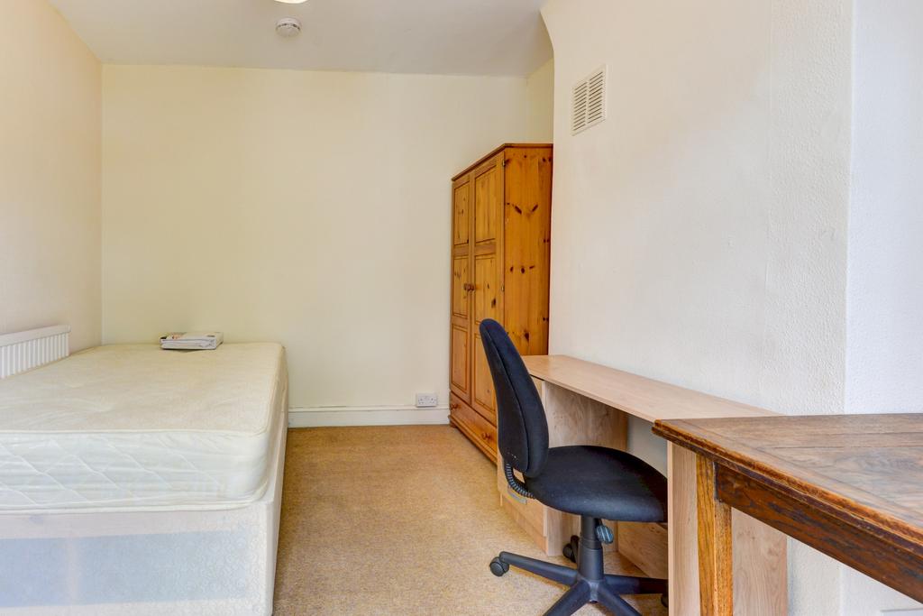 A simple, tidy student bedroom with a bed and a...