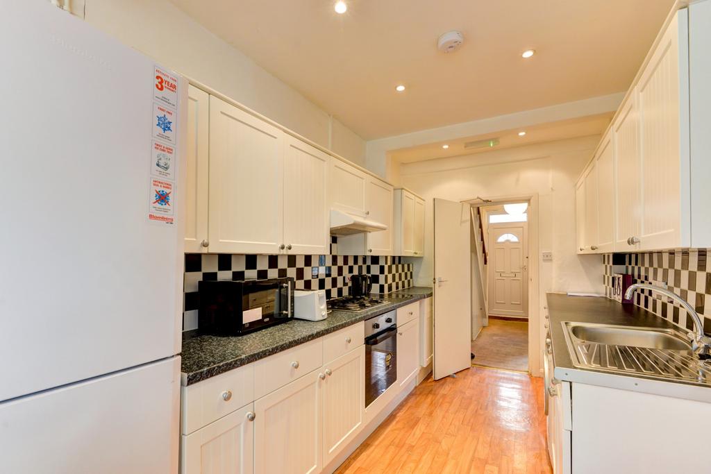A bright and tidy modern kitchen featuring whit...