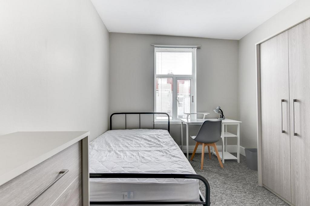 Bright, simply furnished bedroom with a metal f...