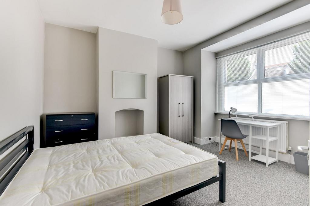 A bright and tidy bedroom featuring a large win...