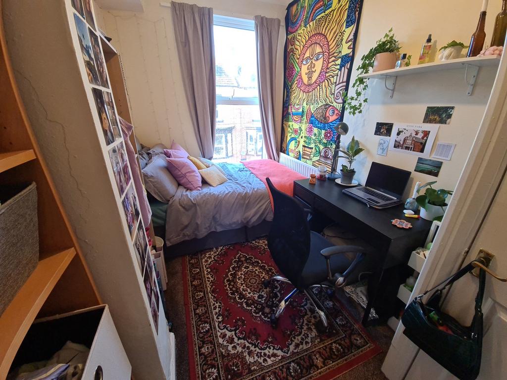 A cozy single bedroom featuring a bed with colo...