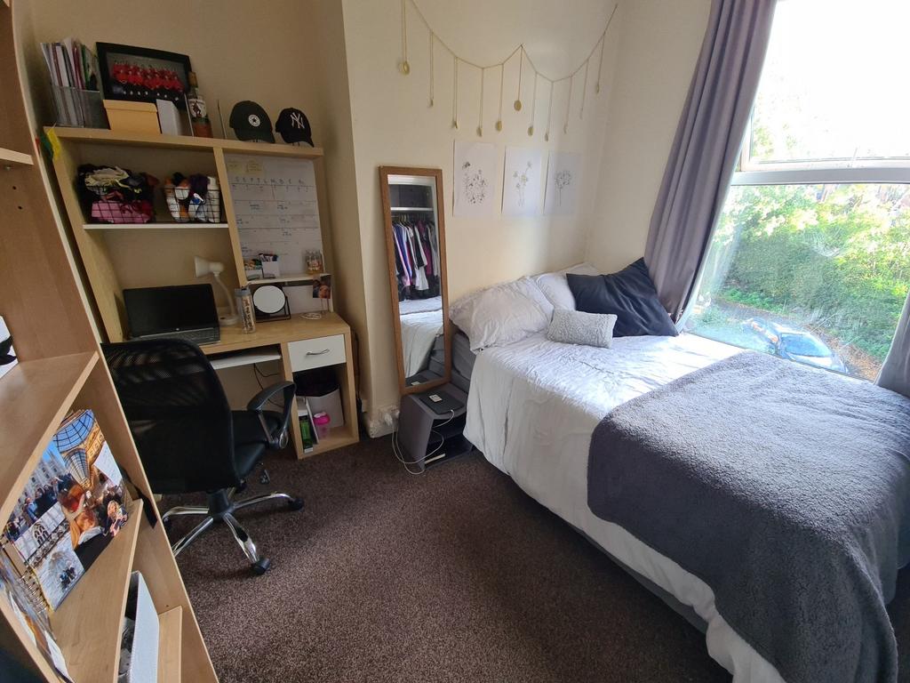 A cozy single bedroom featuring a neatly made b...