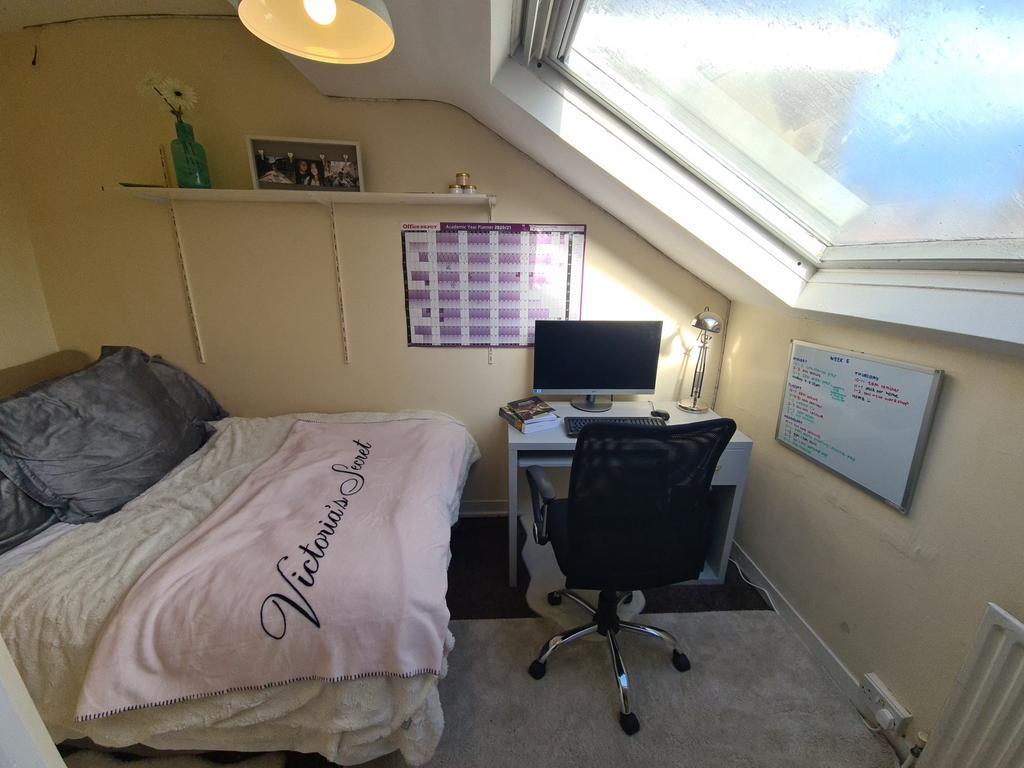 A cozy bedroom featuring a bed with a pink duve...