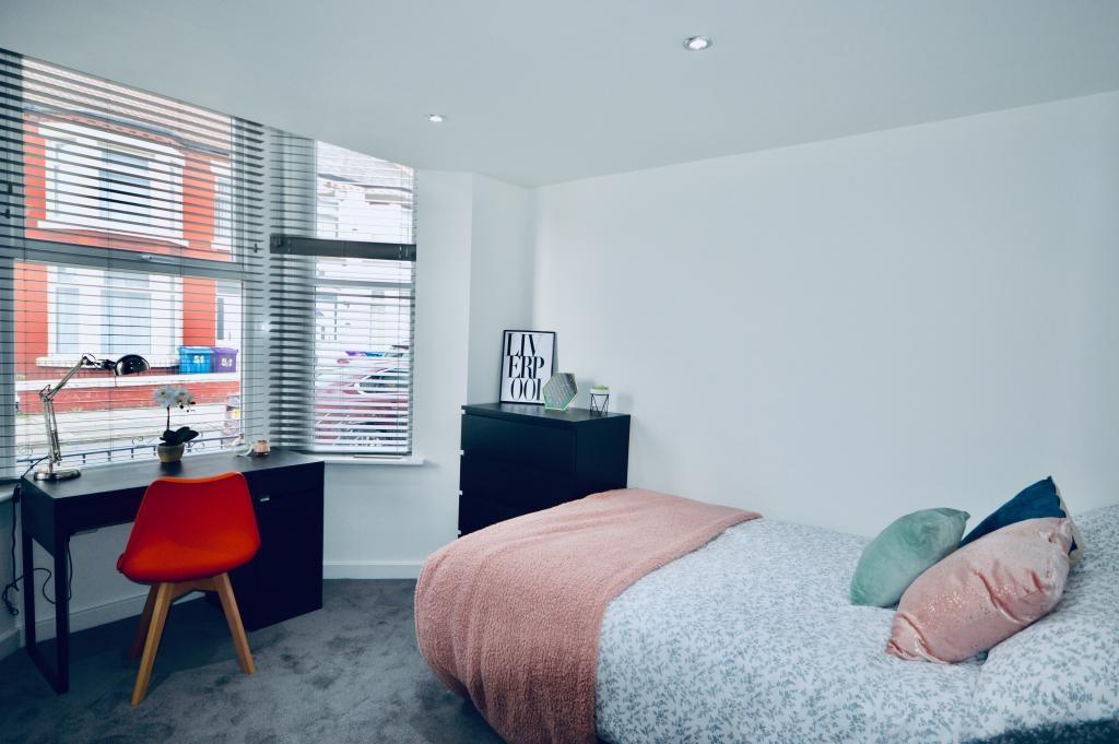 A tidy and well-lit bedroom featuring a comfort...