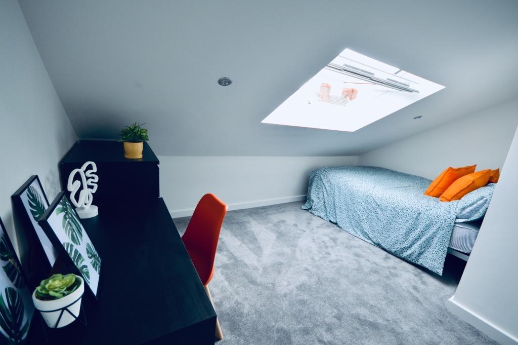 A spacious and bright bedroom featuring a comfo...