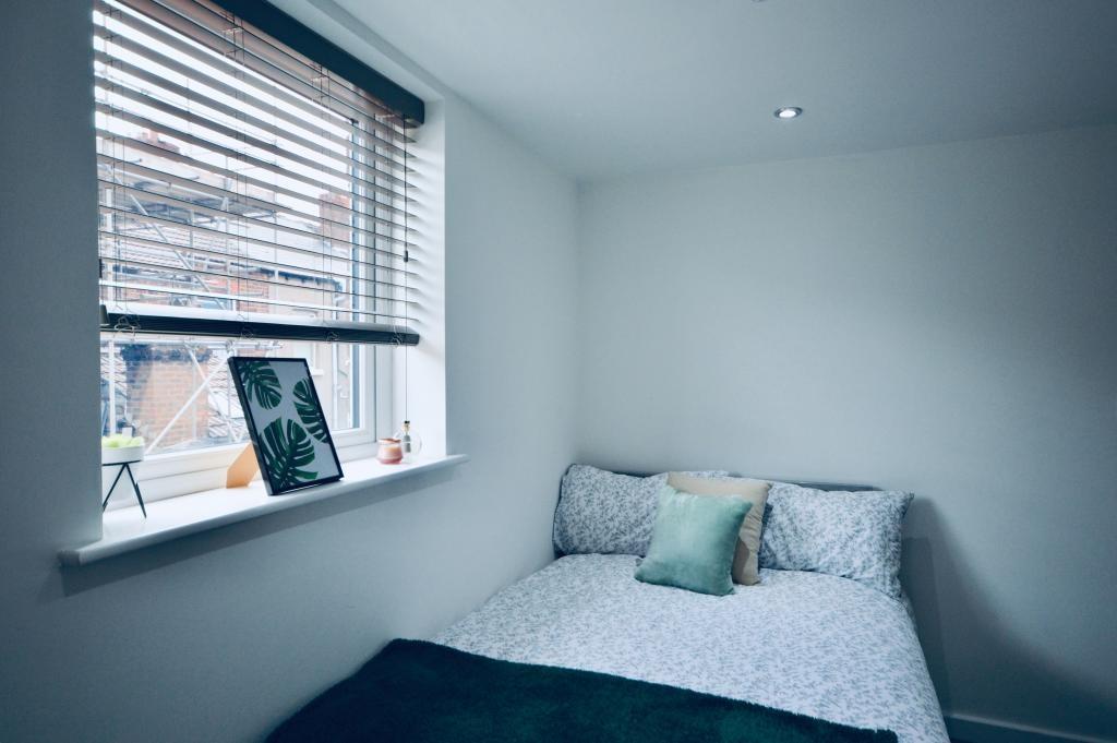 A bright and tidy bedroom featuring a neatly ma...