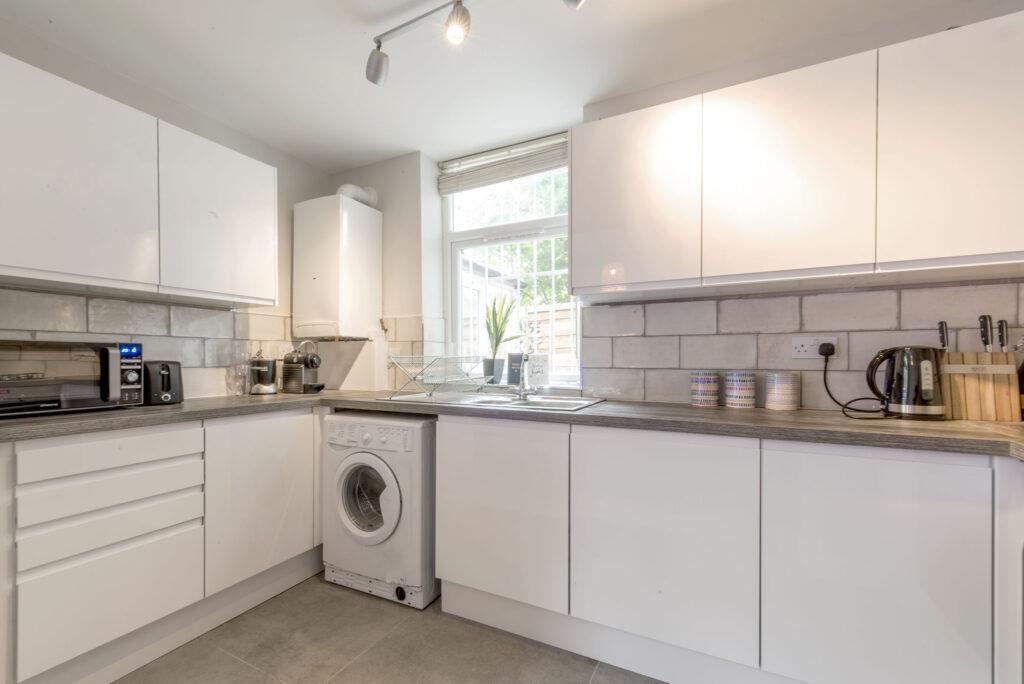 Bright modern kitchen with white cabinetry, int...