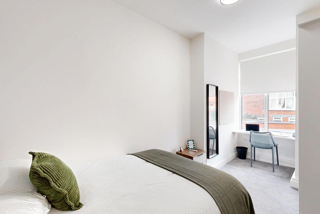 A bright, clean bedroom featuring a bed with a ...