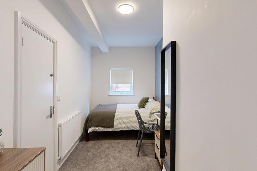 A tidy and well-lit single bedroom featuring a ...