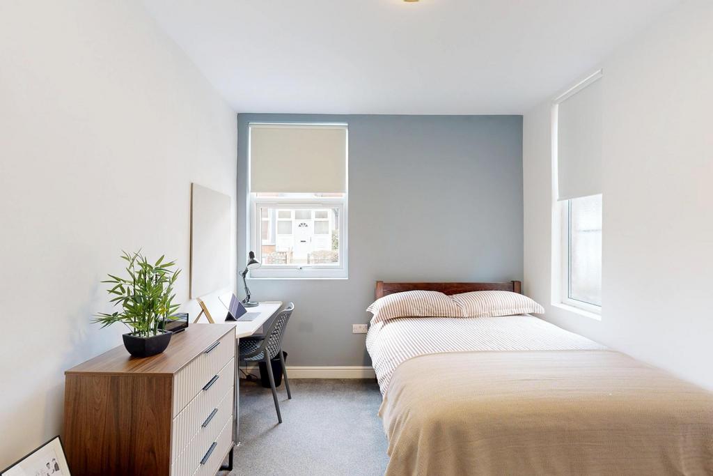 A bright and tidy student bedroom featuring a c...