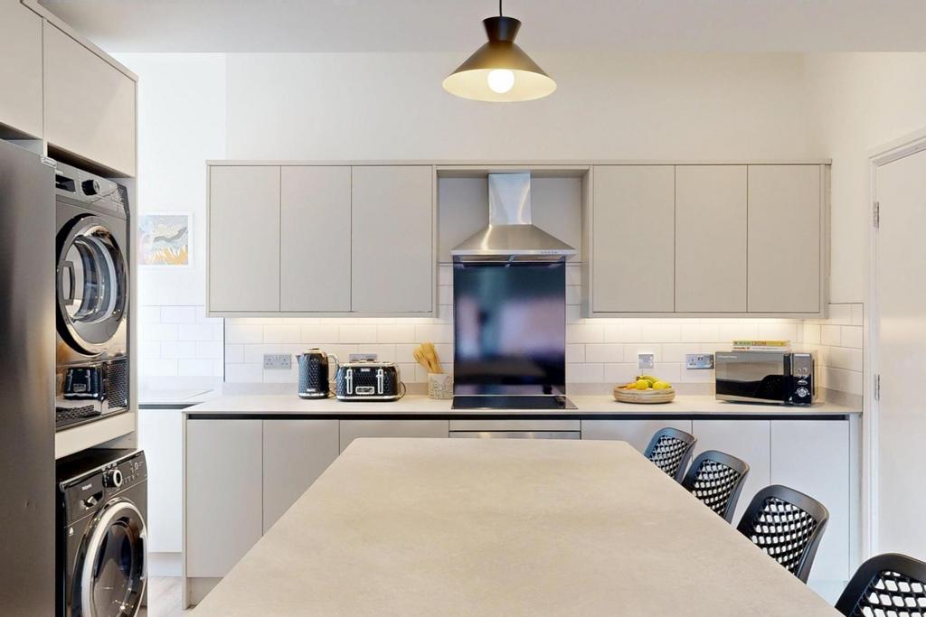A modern and well-lit kitchen featuring clean w...