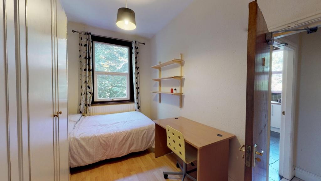 A cozy single bedroom featuring a neatly made b...
