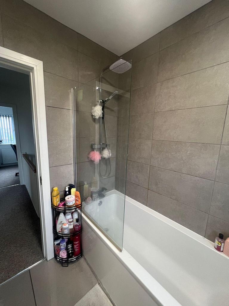 Modern bathroom with tiled walls, a white batht...