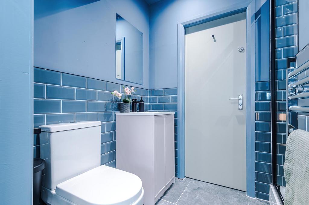 Bright modern bathroom with blue tiled walls, a...