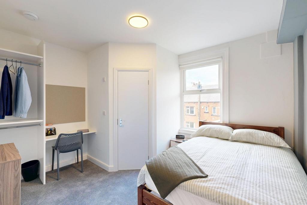 A bright and tidy student bedroom featuring a c...