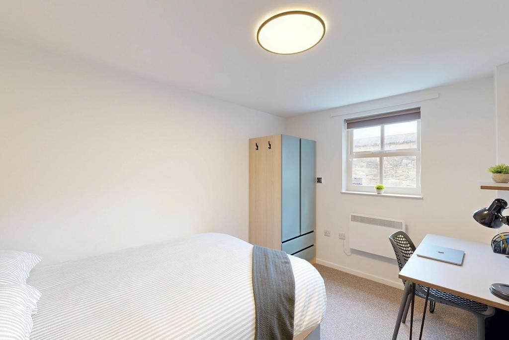 A bright and clean bedroom featuring a single b...
