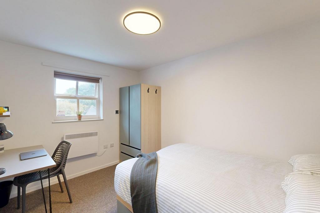 A bright and tidy single bedroom featuring a co...
