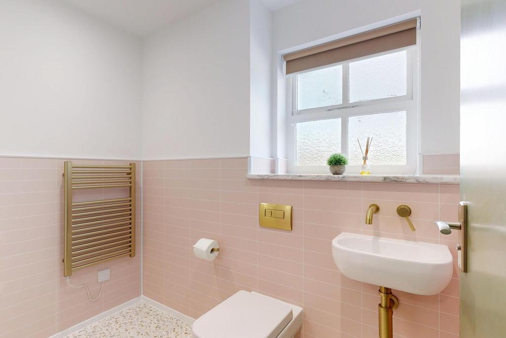 Bright, modern bathroom with pale pink tiled wa...