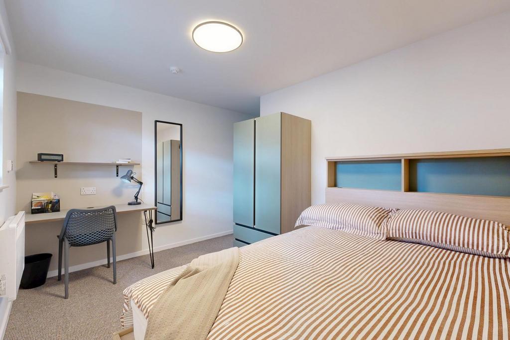 A neatly maintained student bedroom featuring a...