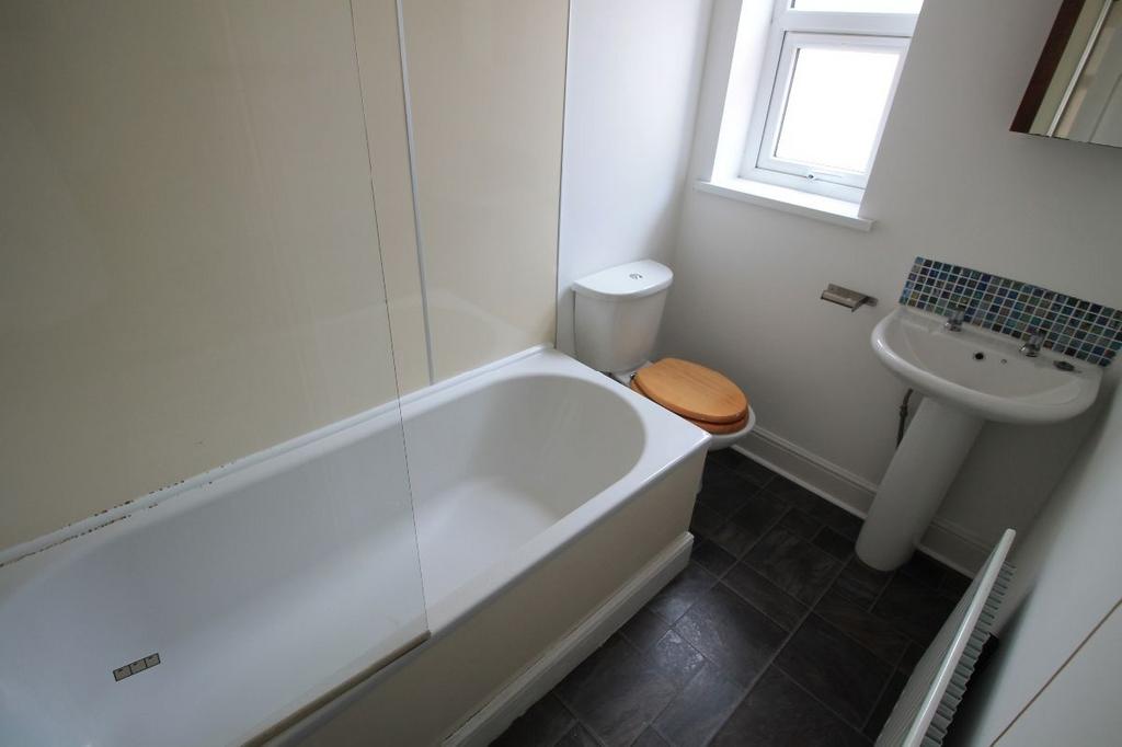 A clean, bright bathroom with a bathtub, a sink...