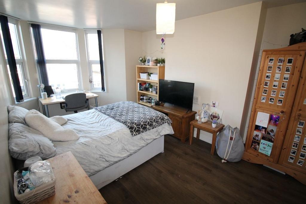 A well-lit, tidy bedroom featuring a comfortabl...