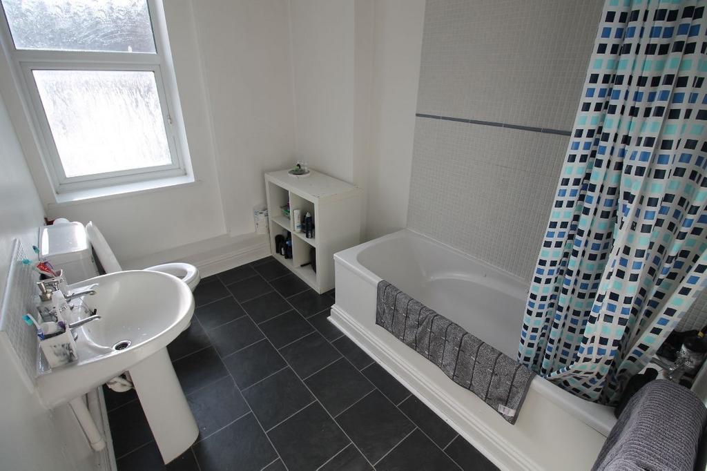 A clean and bright bathroom featuring a bathtub...