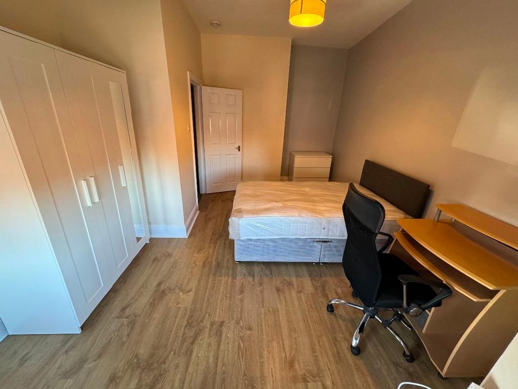 A well-lit double bedroom with a comfortable be...