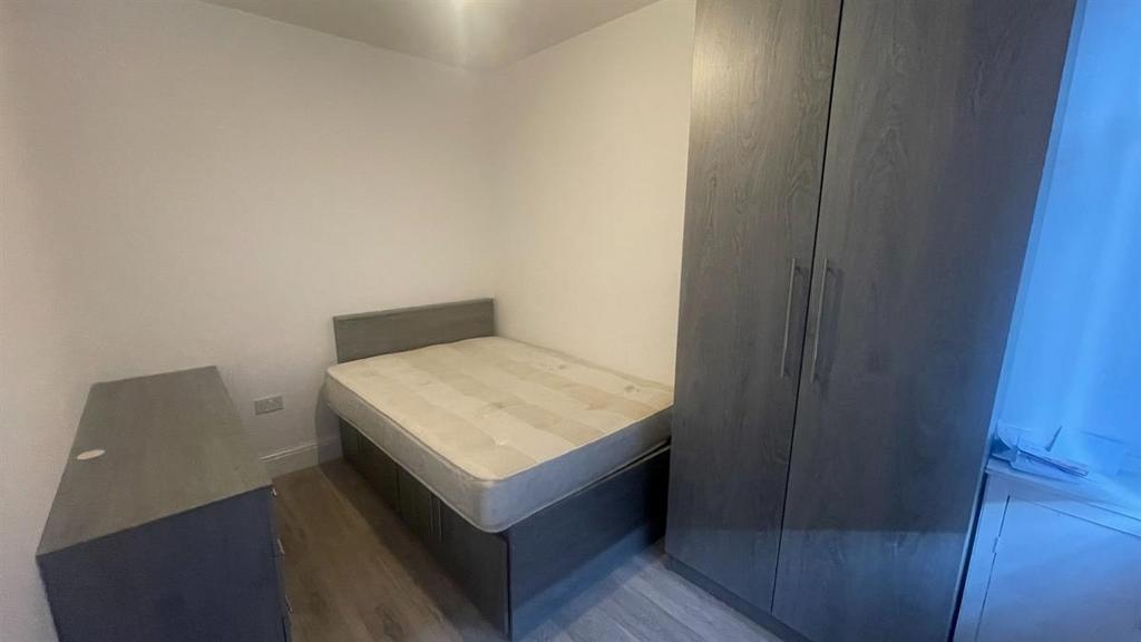 A cozy single bedroom featuring a bed and basic...