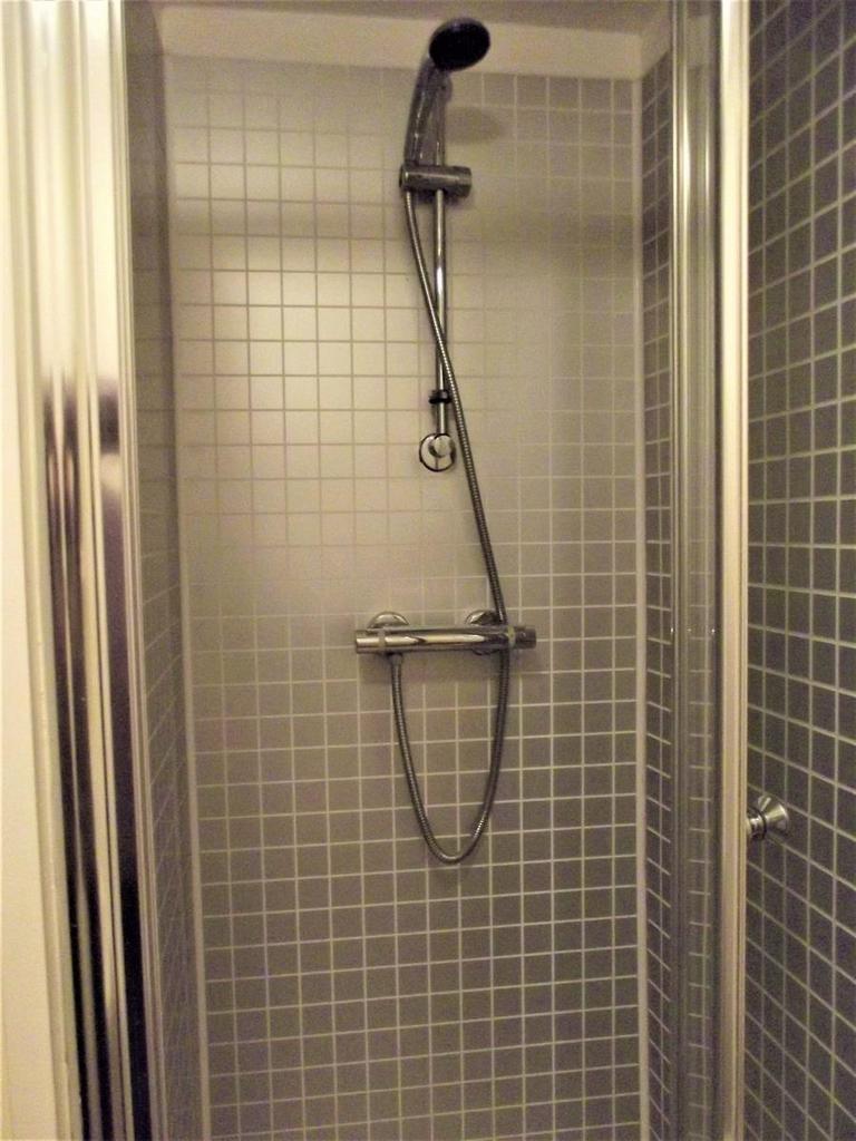 A clean and modern shower unit with a tiled int...