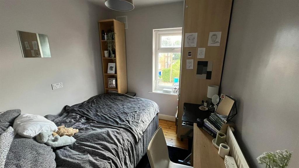 A cozy single bedroom featuring a bed with bedd...