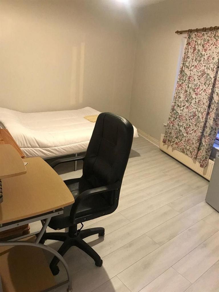 A tidy single bedroom featuring a bed with whit...