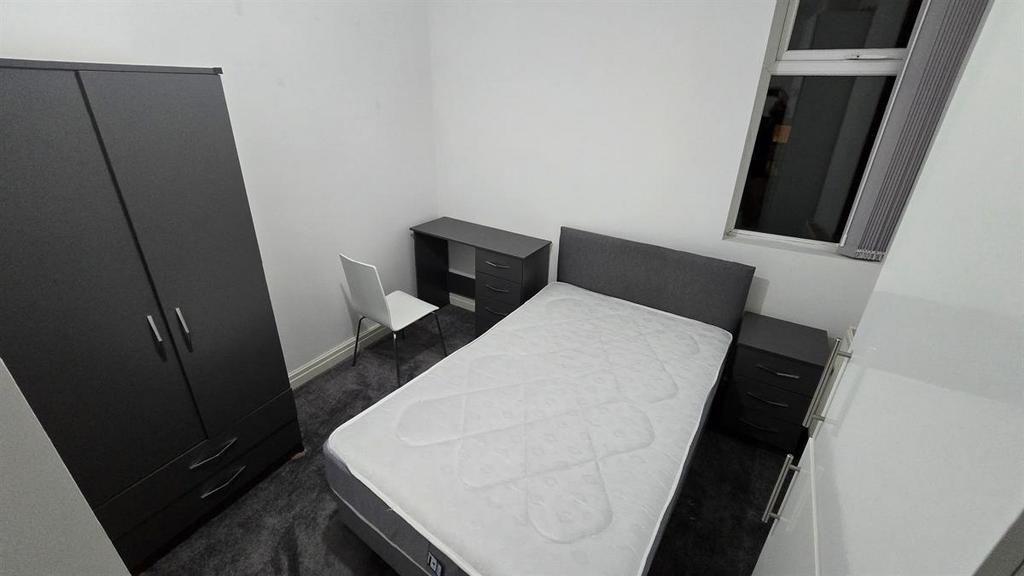 A simple, neatly maintained bedroom featuring a...