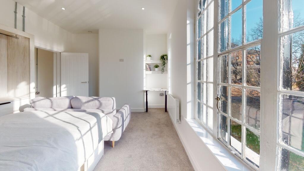 Bright and spacious master bedroom with large w...