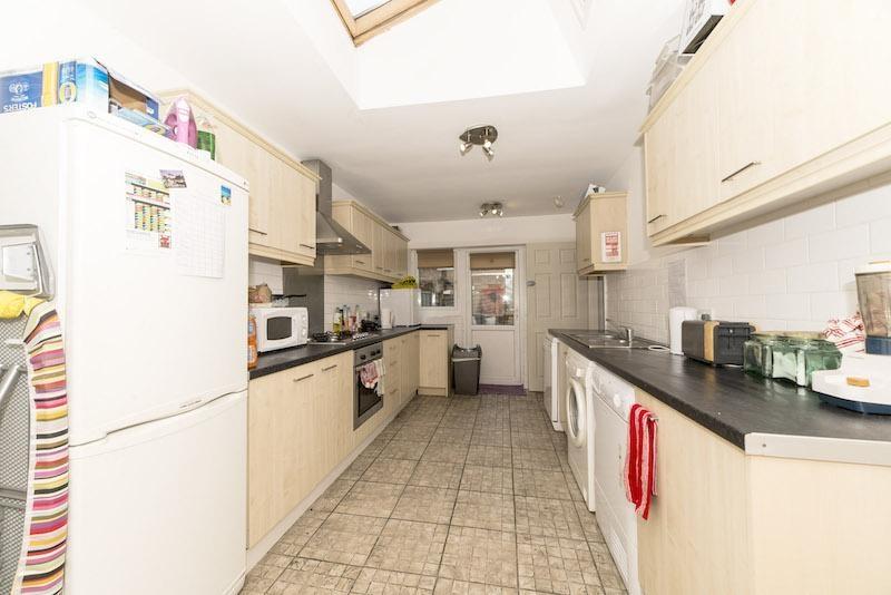 Bright galley-style kitchen with pale wood cabi...