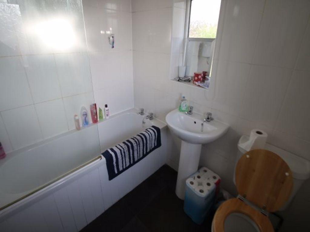 A clean and bright bathroom featuring a bathtub...