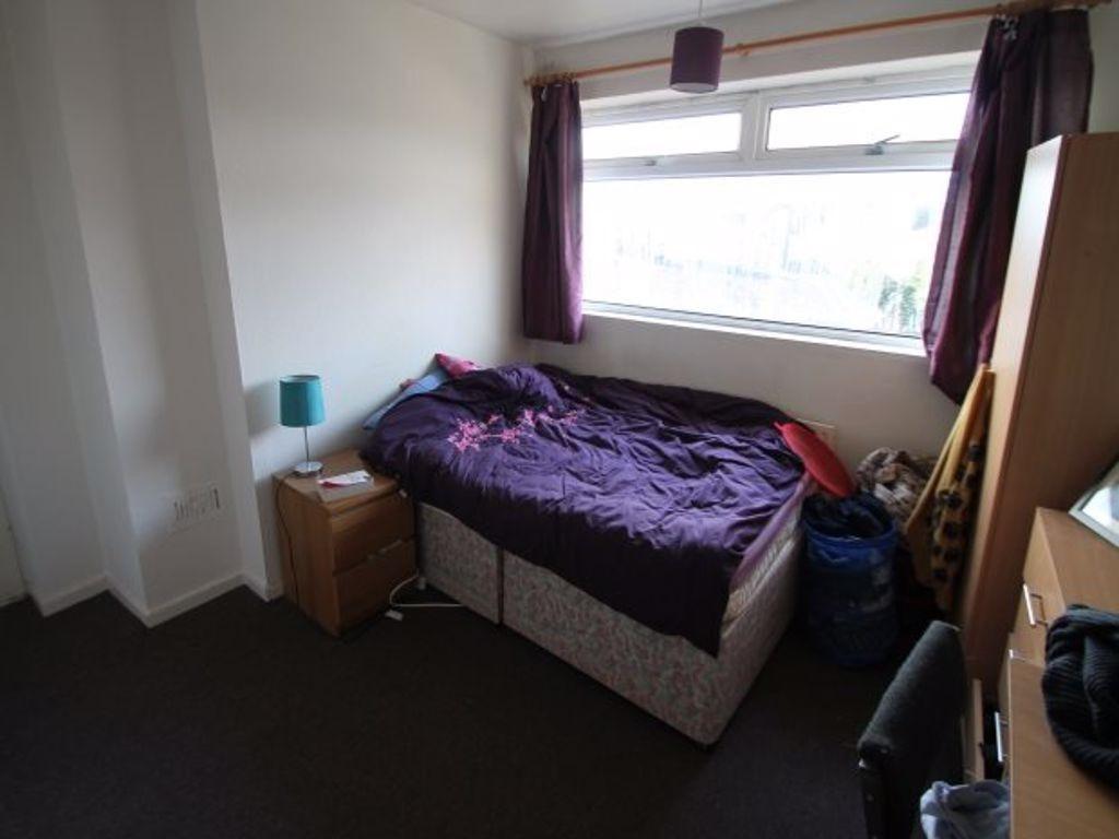 A cozy single bedroom featuring a bed with purp...