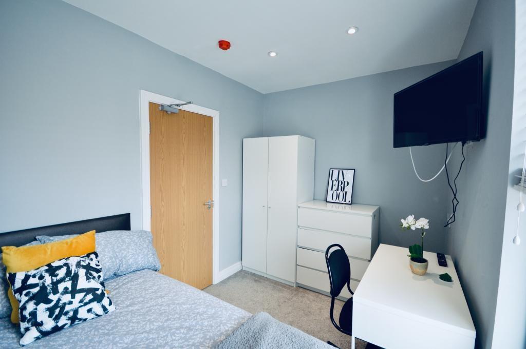 A modern bedroom featuring a neatly made bed wi...