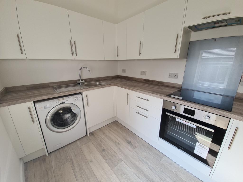 A modern kitchen with clean white cabinets, a w...